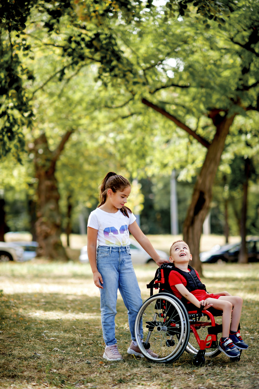 un garçon en fauteuil roulant accompagné de sa grande soeur dans le parc ICARE Center
